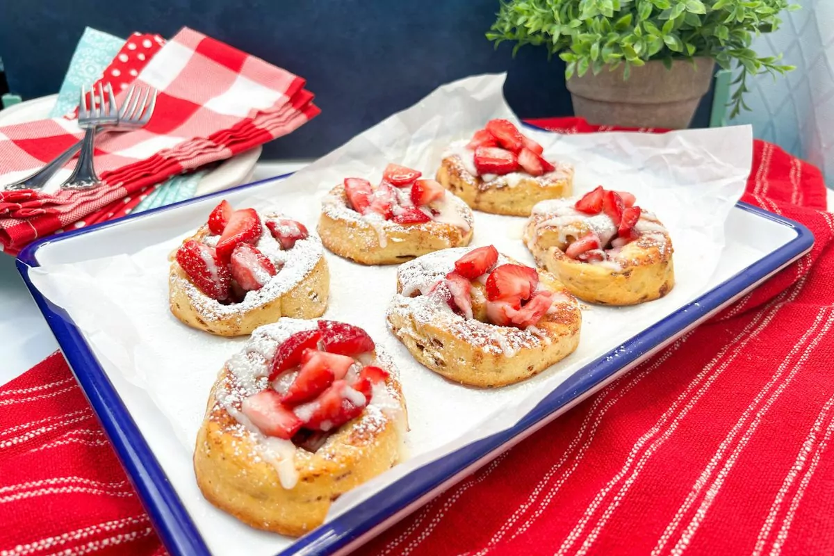 white tray with blue trim holding 6 strawberry cinnamon rolls.