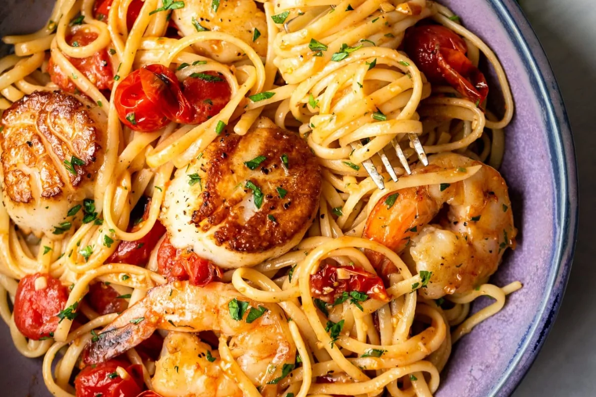 a plate of pasta with shrimp and tomato