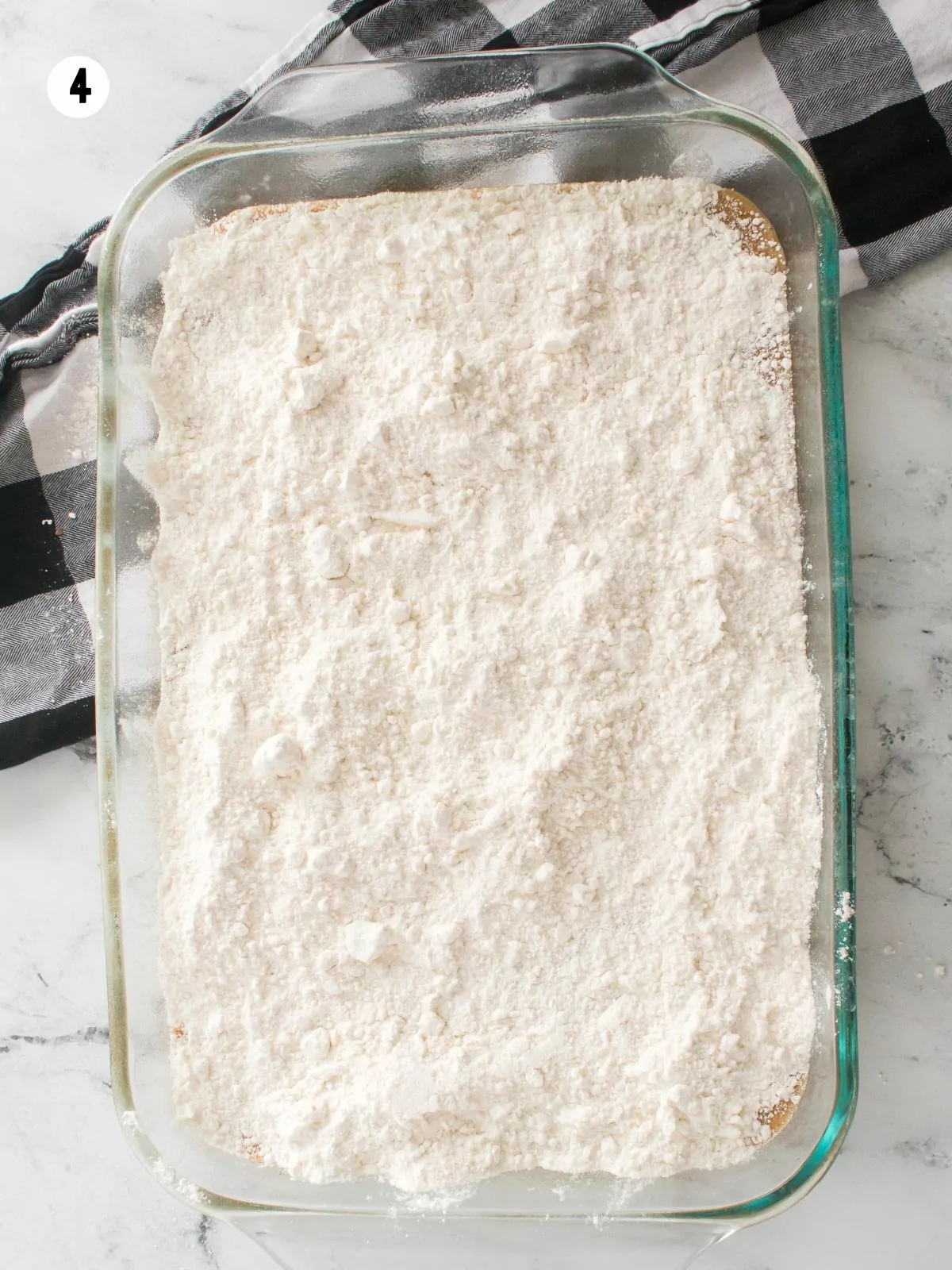 cake mix on top of cake batter in glass baking dish.