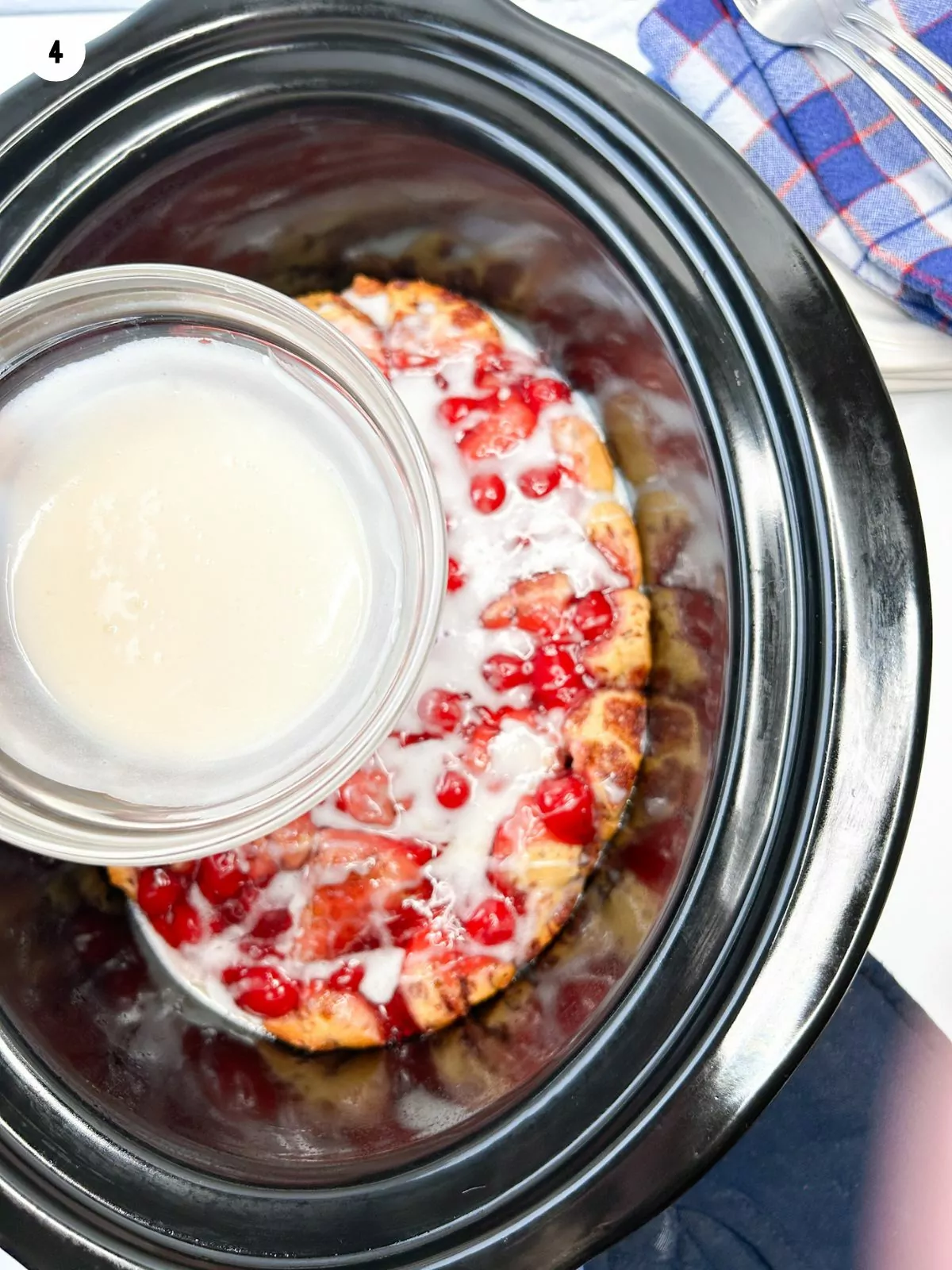 Icing in a small bowl pouring over the baked cherry cinnamon rolls