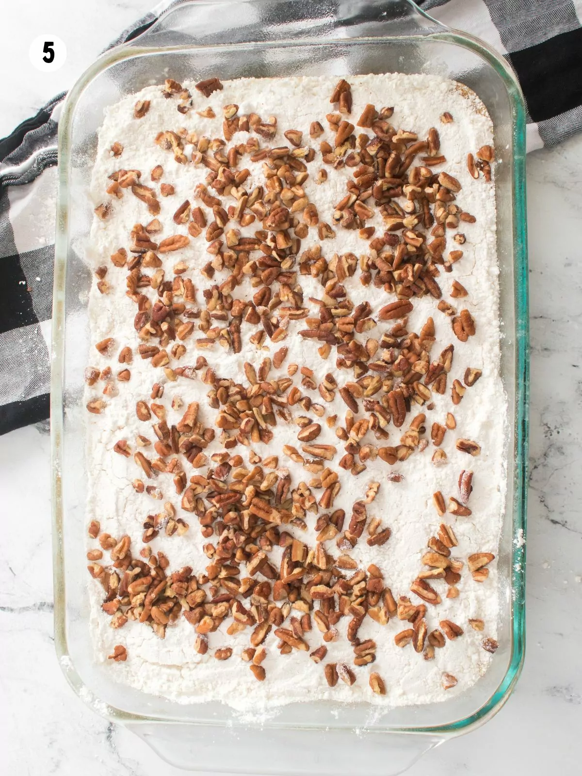 pecans and cake mix in glass baking dish.