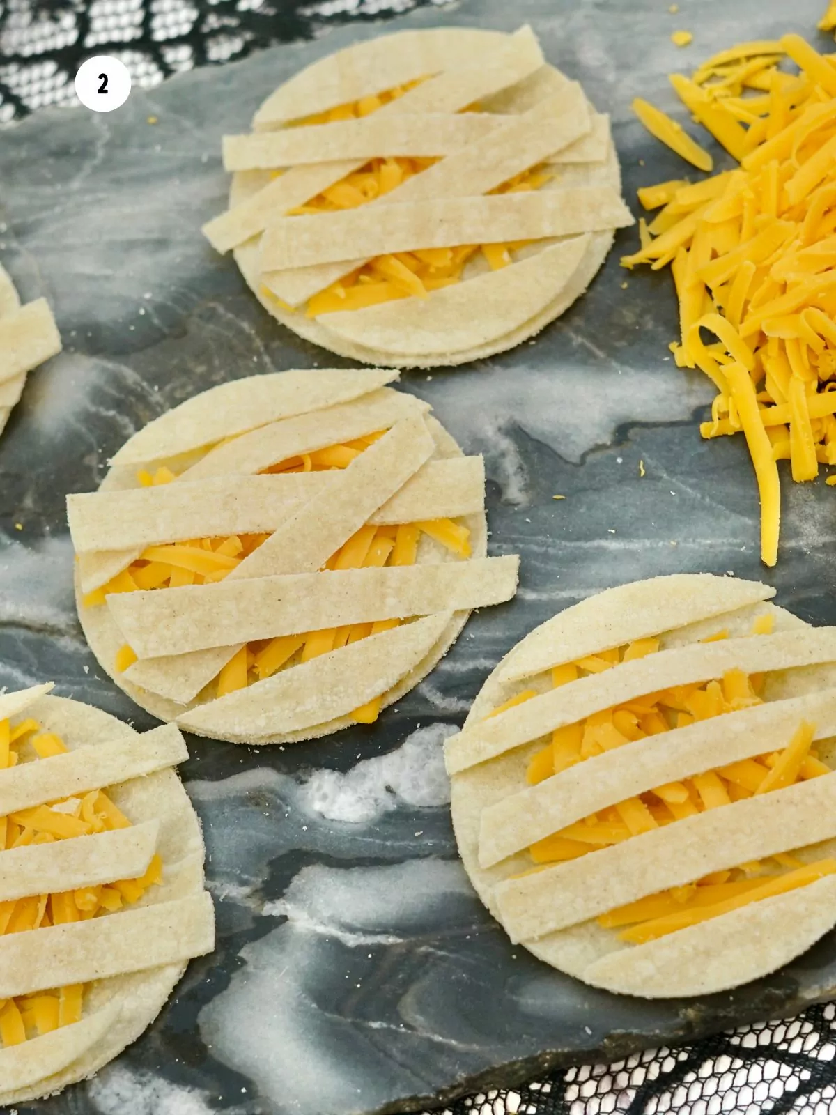 crisscross flour tortilla pieces on top of cheese to form a sandwich.