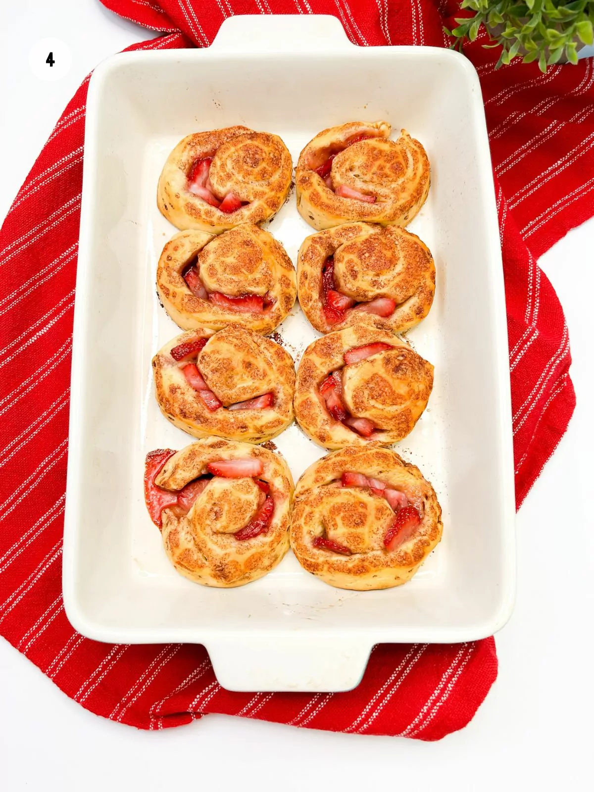 baked rolls in casserole dish on top of red striped dish towel.