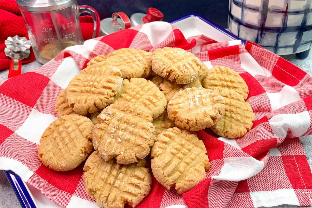 Peanut butter cookies piled on top of a red plaid napkin.