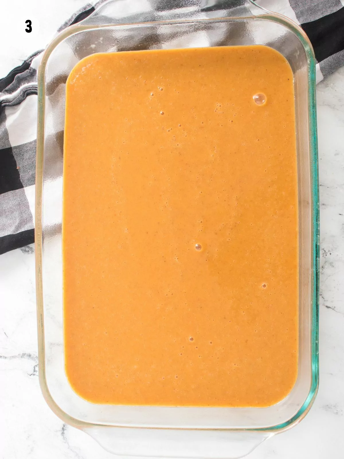 pumpkin cake batter in glass baking dish.