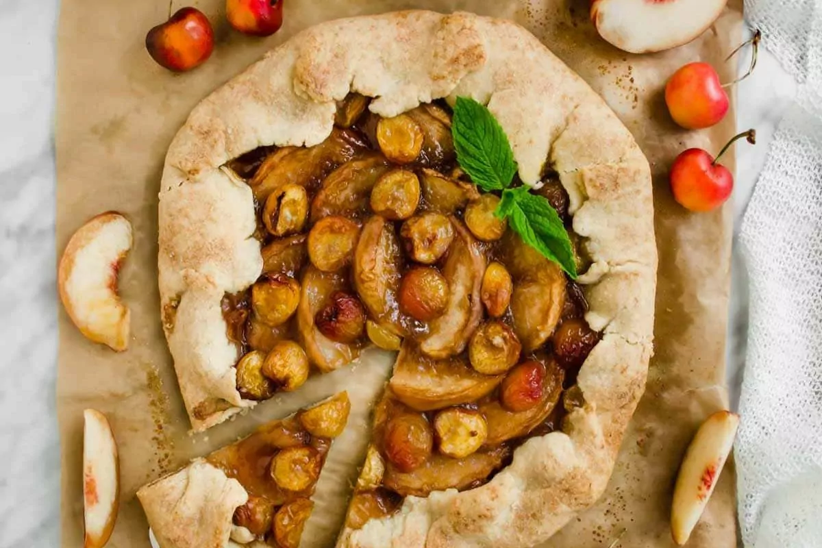 A rustic galette filled with white peach slices and cherries.