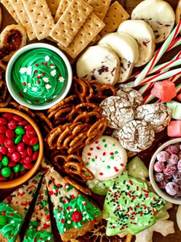 a charcuterie board full of cookies, candy, fresh fruit, and other seasonal sweet treats