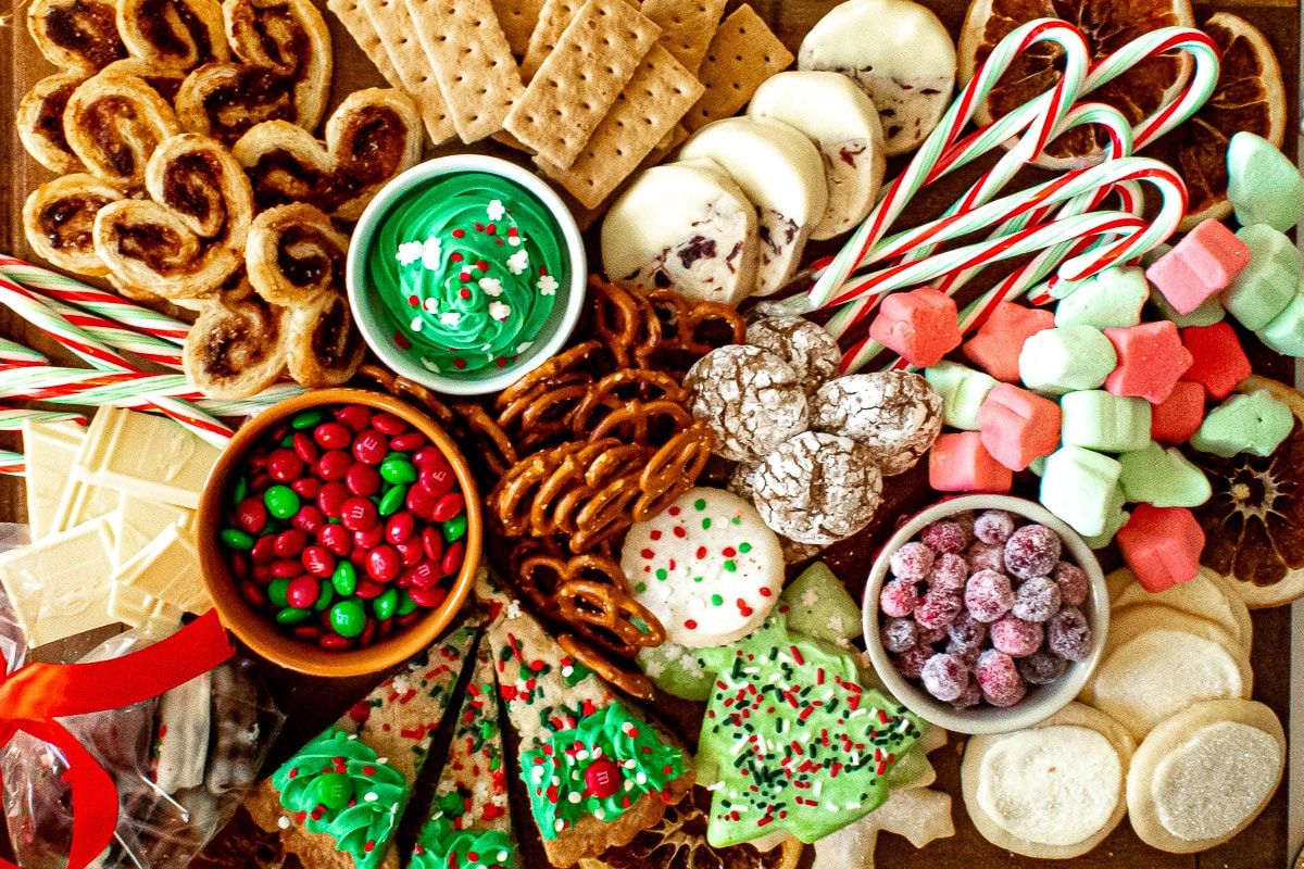 a charcuterie board full of cookies, candy, fresh fruit, and other seasonal sweet treats