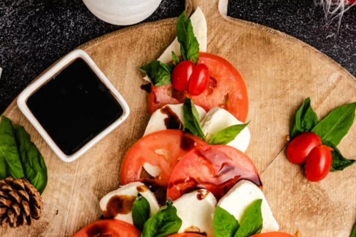 a tree shape charcuterie with fresh mozzarella, tomatoes, basil, and then topped with a balsamic glaze