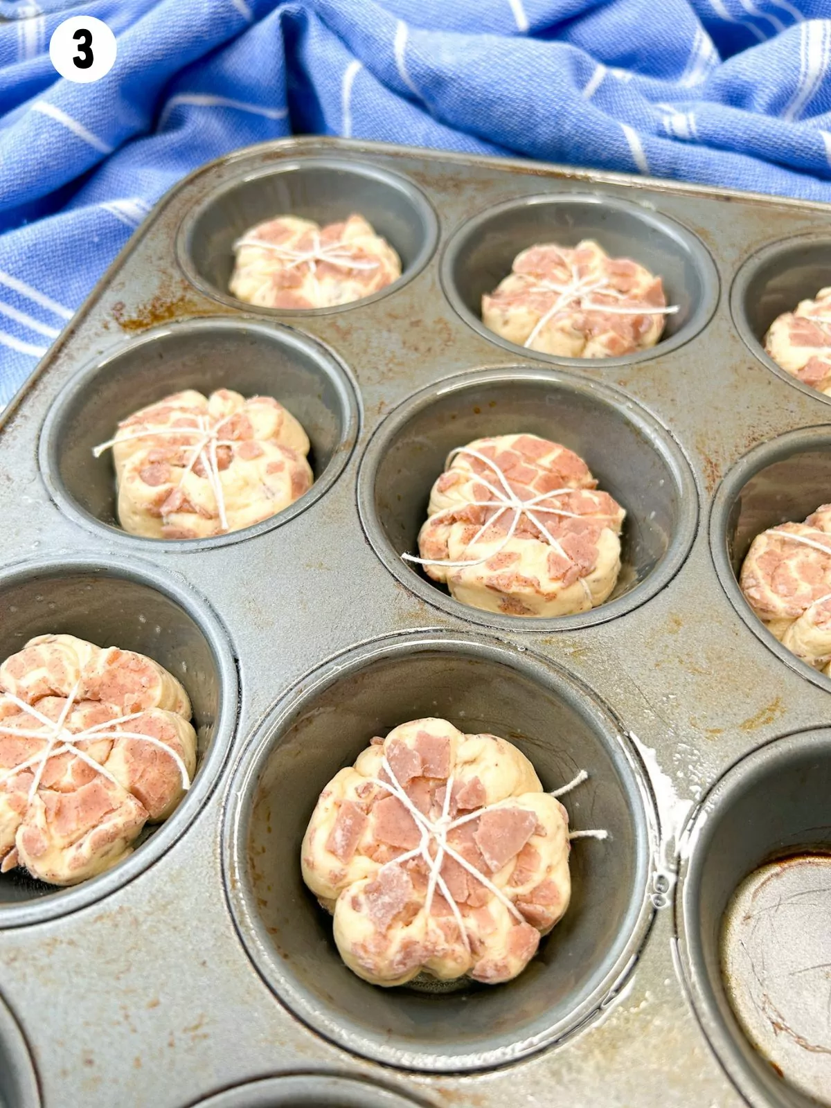 cinnamon rolls with kitchen twine in muffin pan.