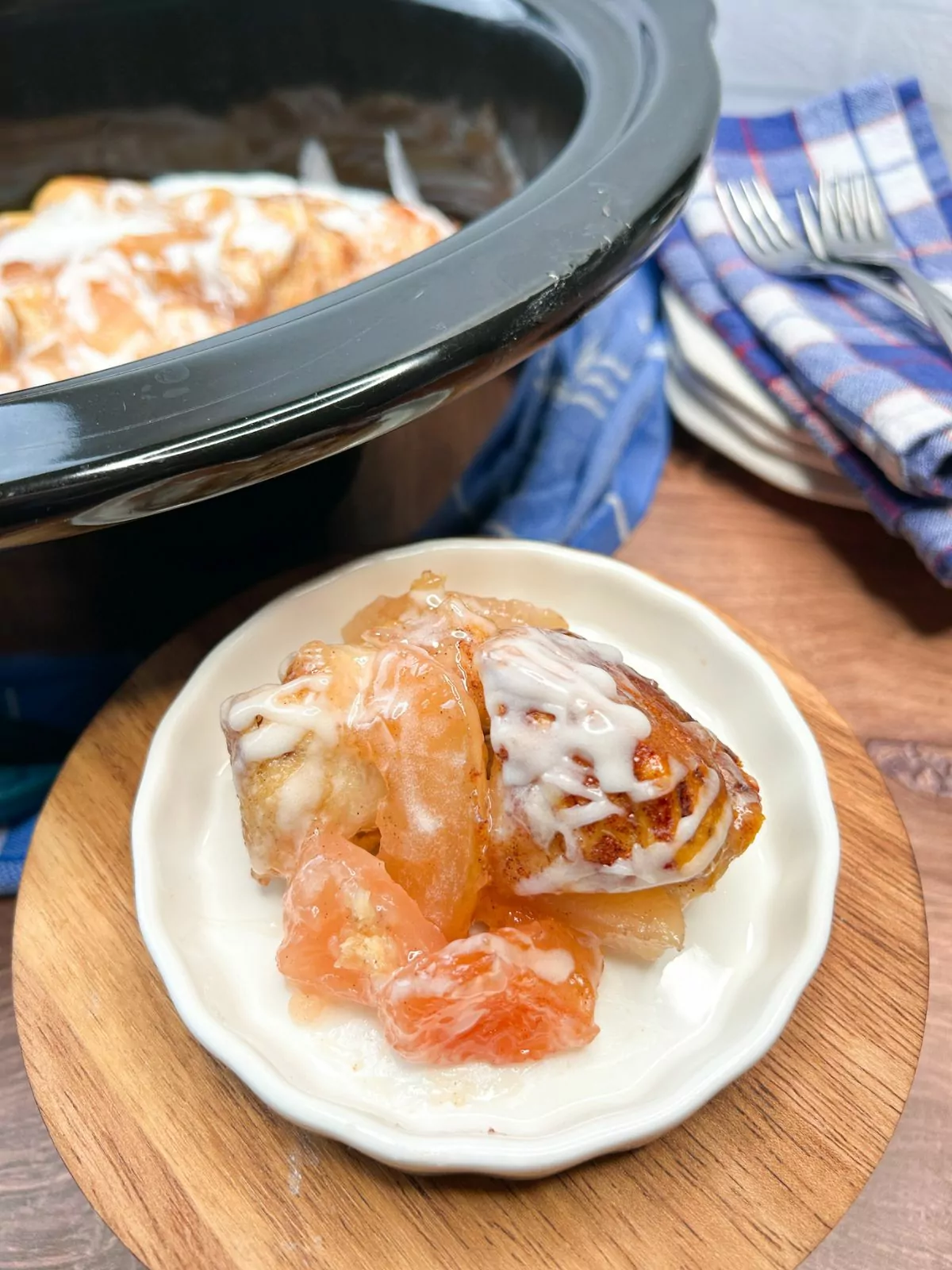 Crock Pot Cinnamon Rolls with Apple Pie Filling served on a white plate with the crock pot in the background