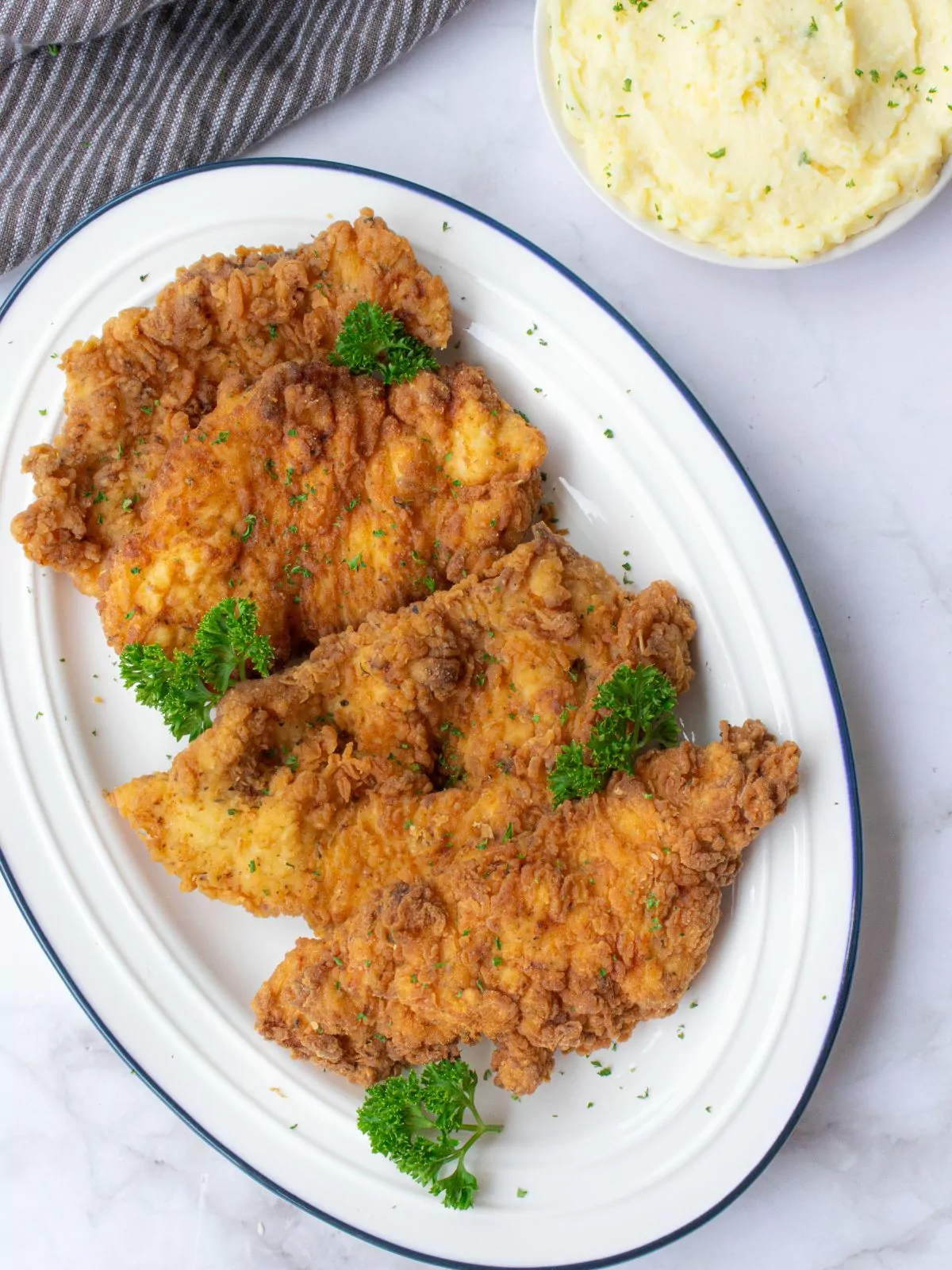 a plate of fried chicken cutlets with sprigs of parsley.