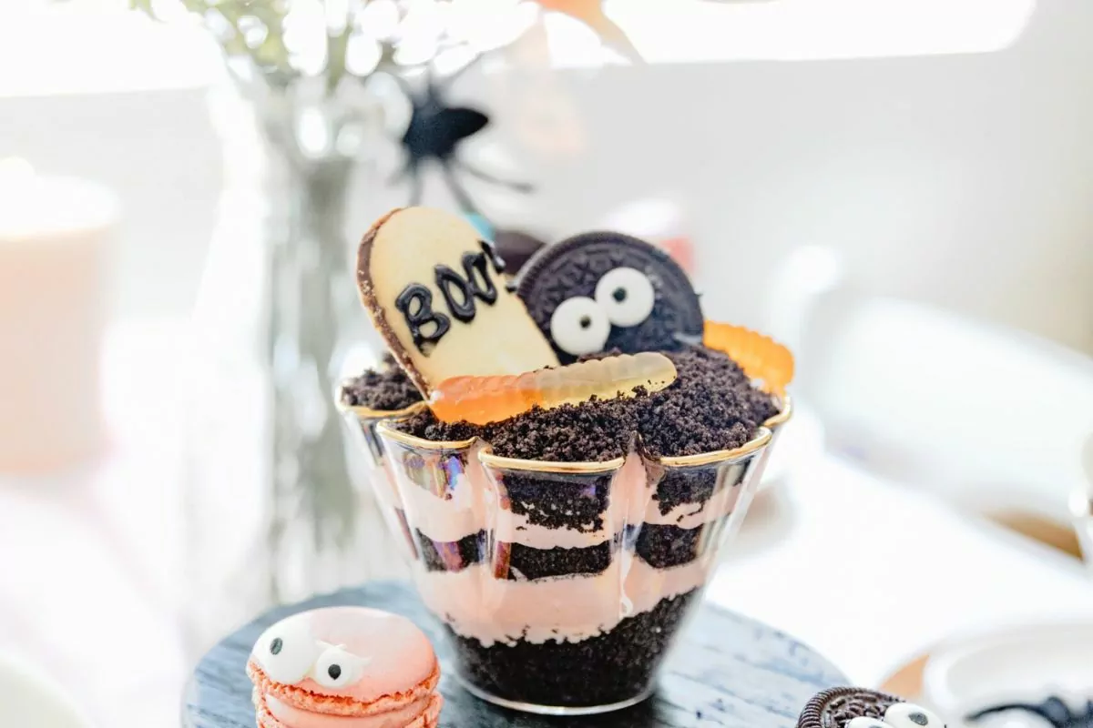 A dirt cake made festive for Halloween with candy, cookies and pudding with cake.