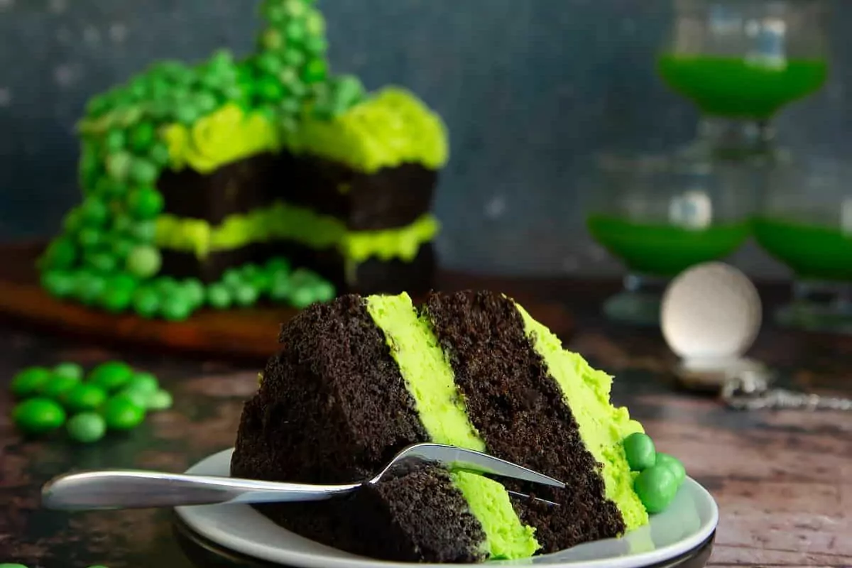 a layer cake with green frosting, candy and a gravity defying touch.