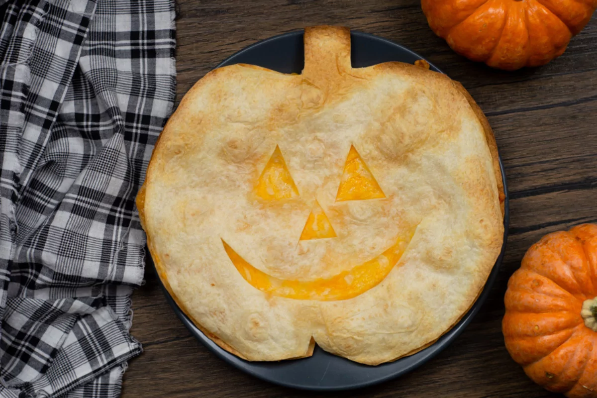 a quesadilla with a jack o lantern face and cheese center.