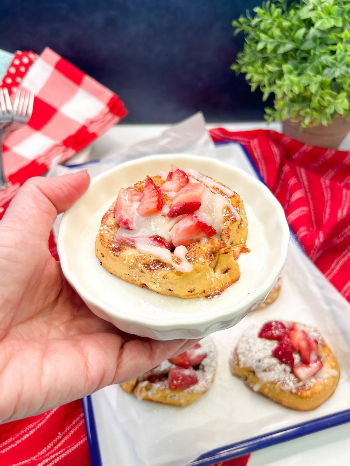 small plate with one cinnamon roll with sliced strawberries.