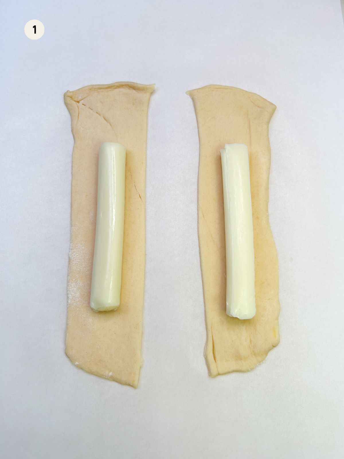 two cheese sticks on top of crescent roll dough.