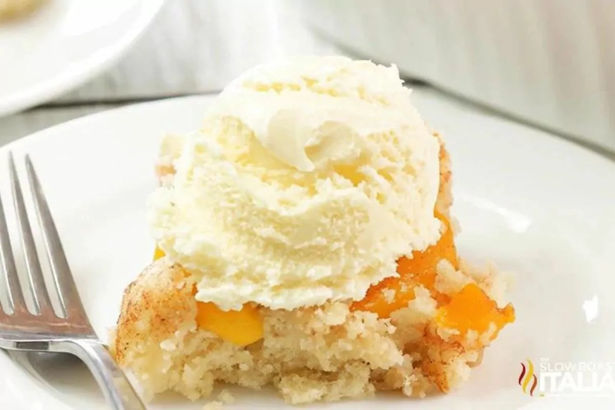 A plate with peach cobbler dump cake on it, with ice cream over the top.