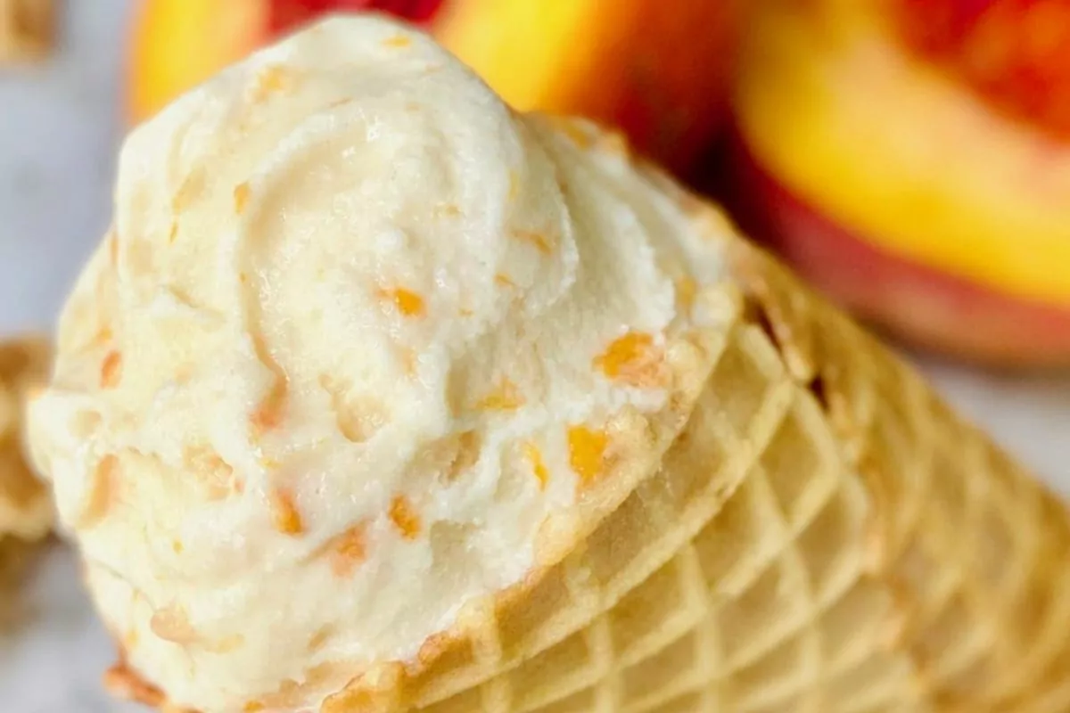 A waffle cone filled with homemade peach ice cream.