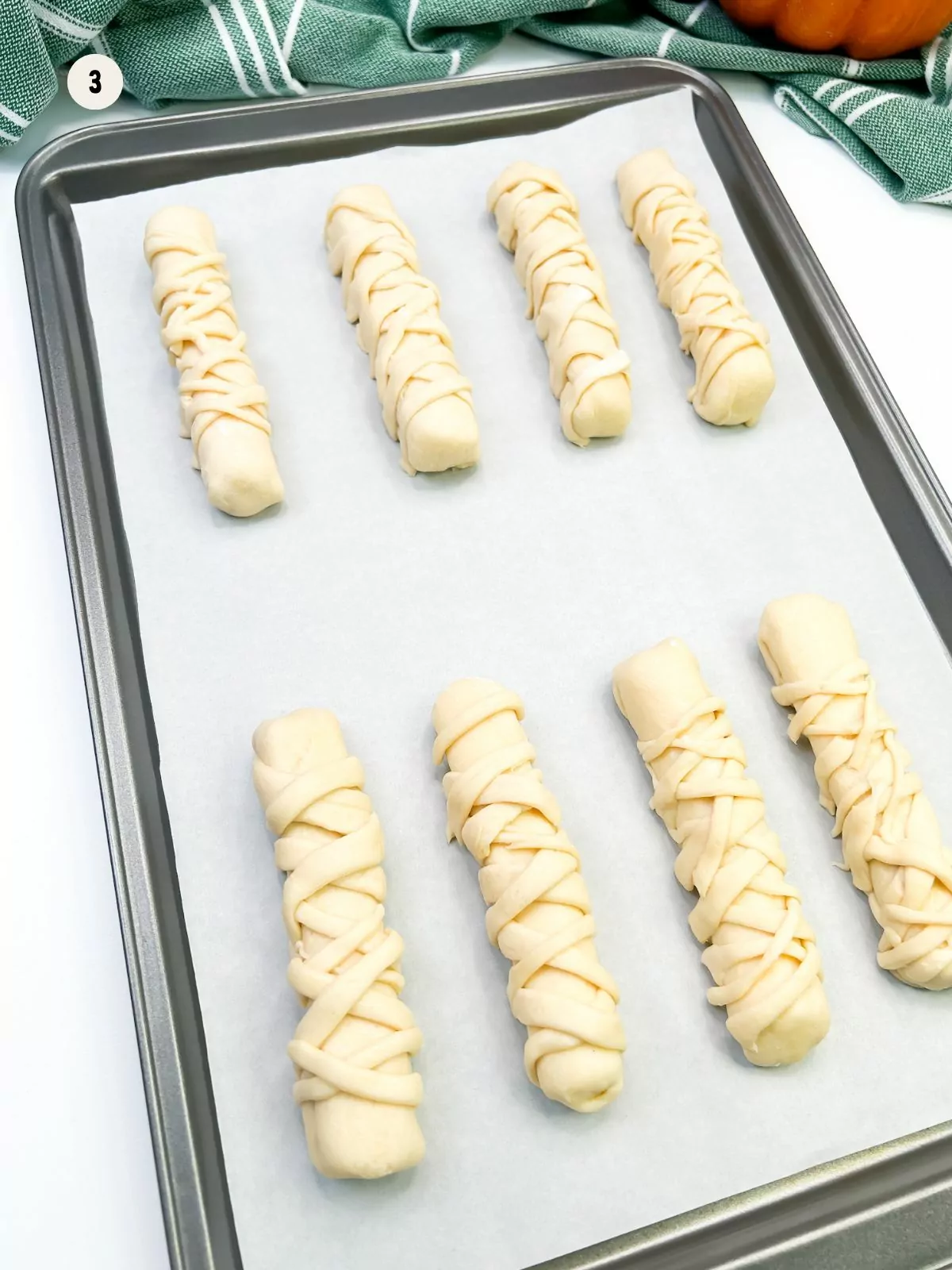 shaped and decorated mummies on baking sheet with parchment paper.