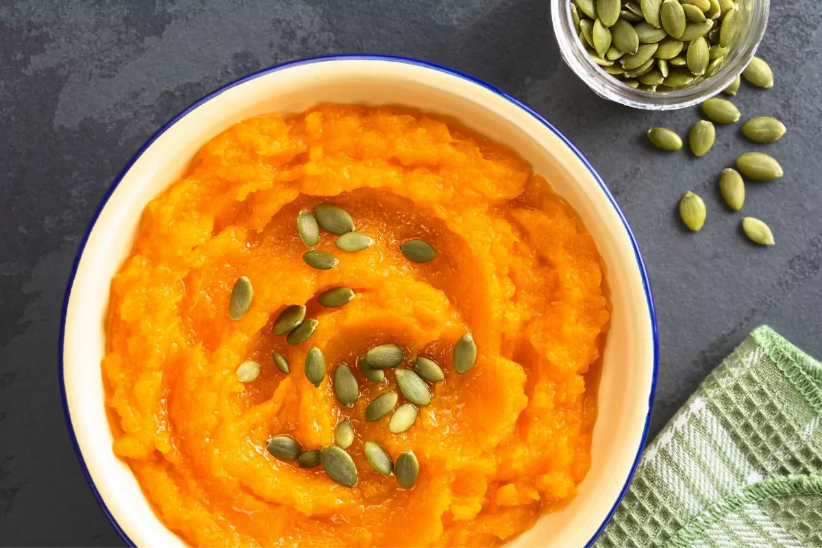 bowl of pumpkin puree with pumpkin seeds on top.