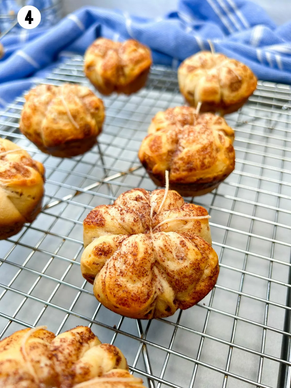 cinnamon rolls baked with string tied around on cooling rack.