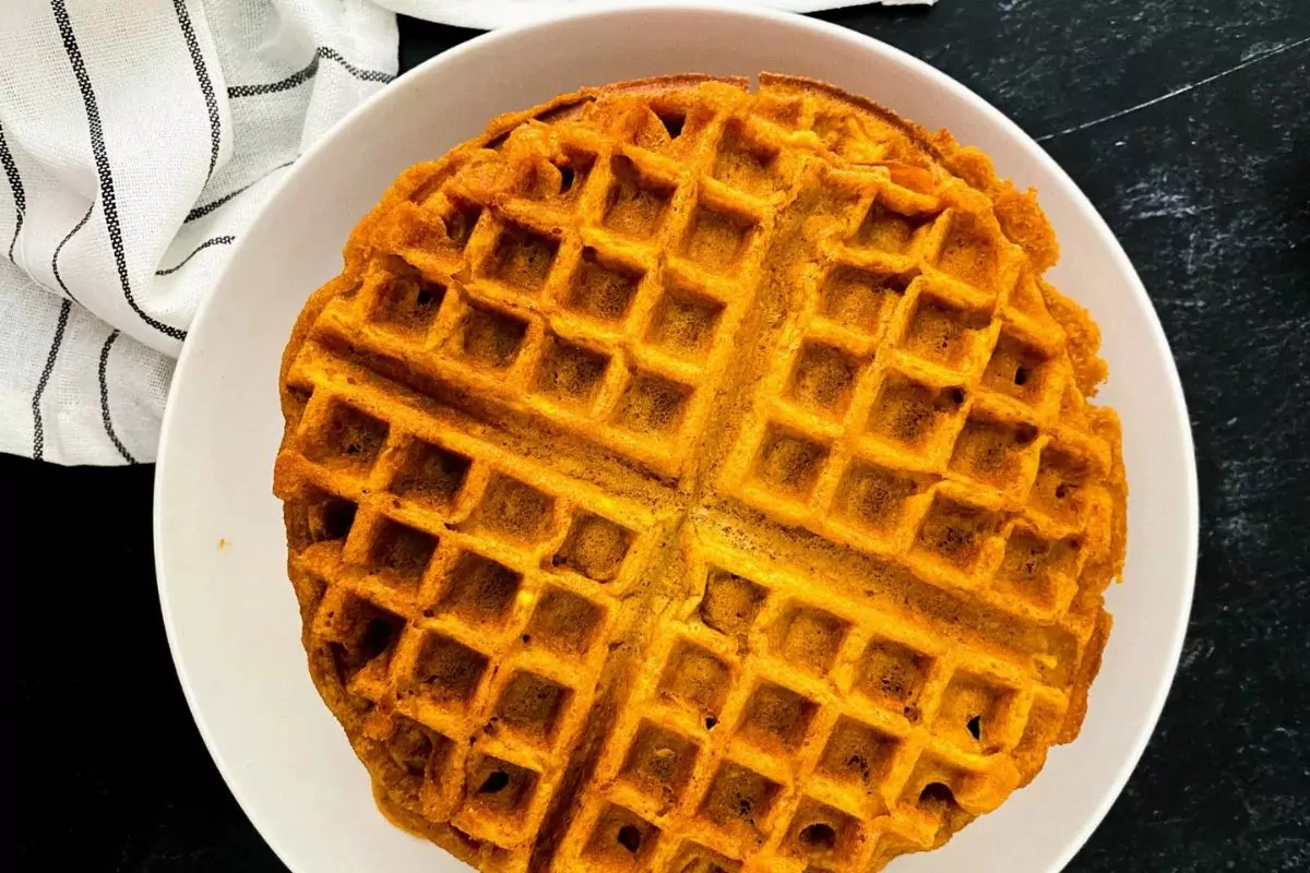 one large pumpkin waffle on white plate.