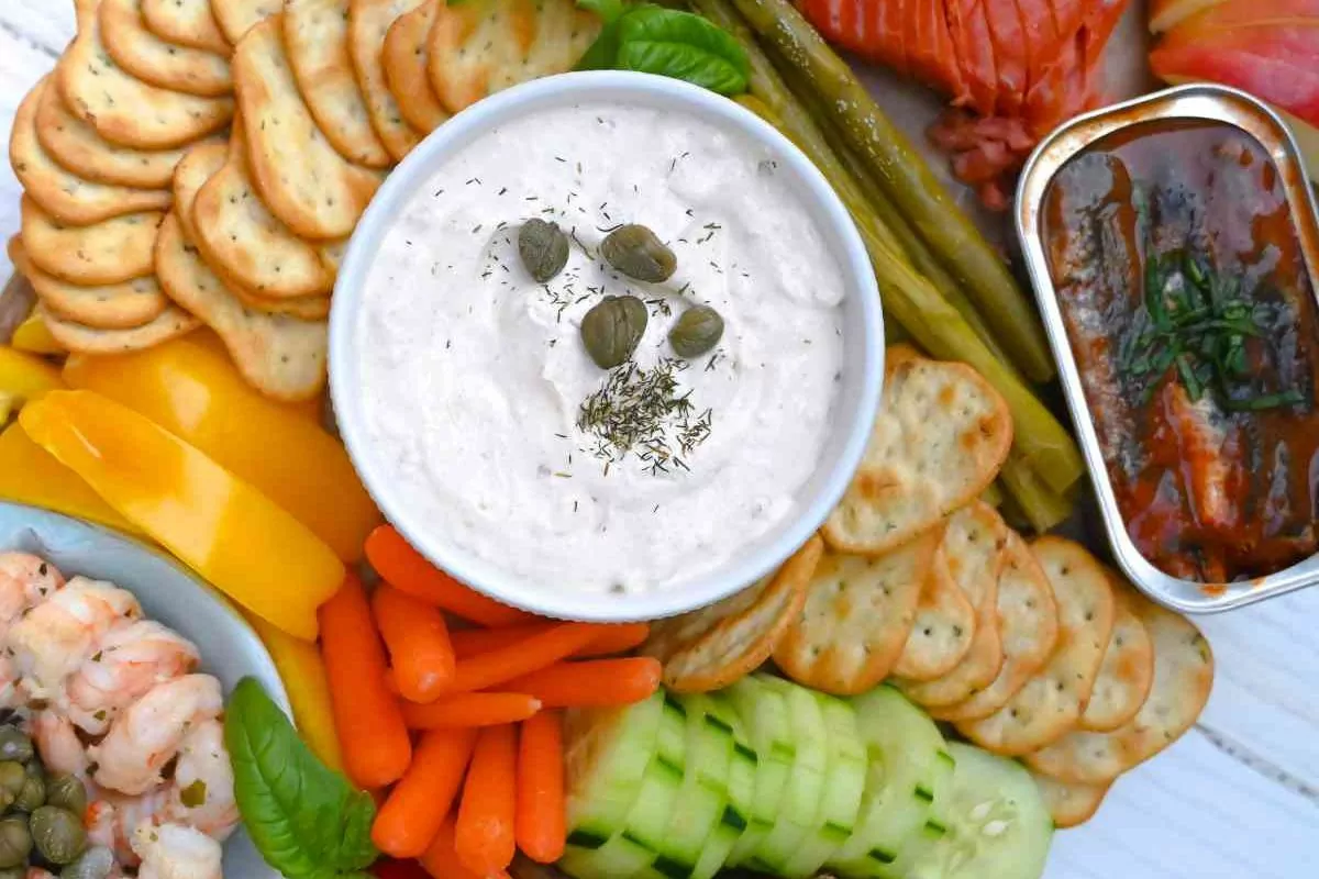 a board with smoked salmon, oysters, crab dip and more with veggies, crackers and nuts