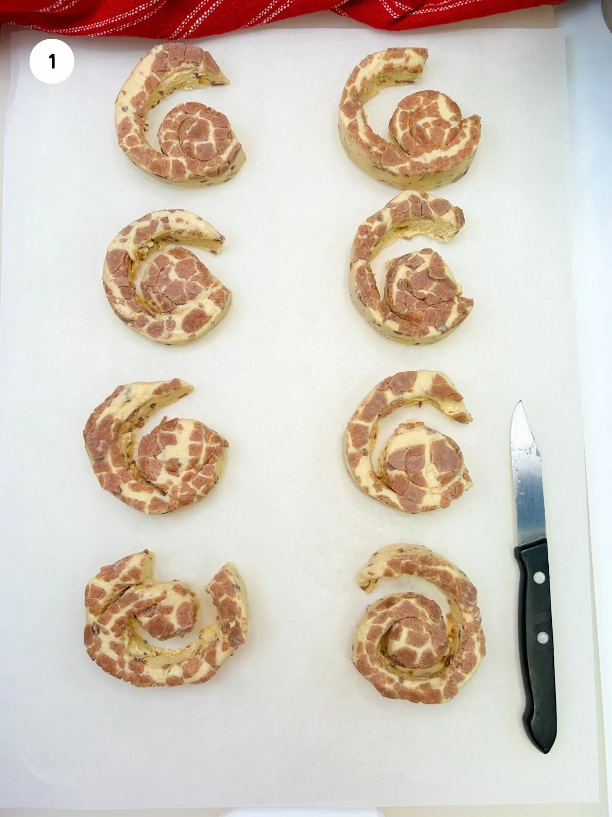 cinnamon rolls on parchment paper unrolled with small knife.