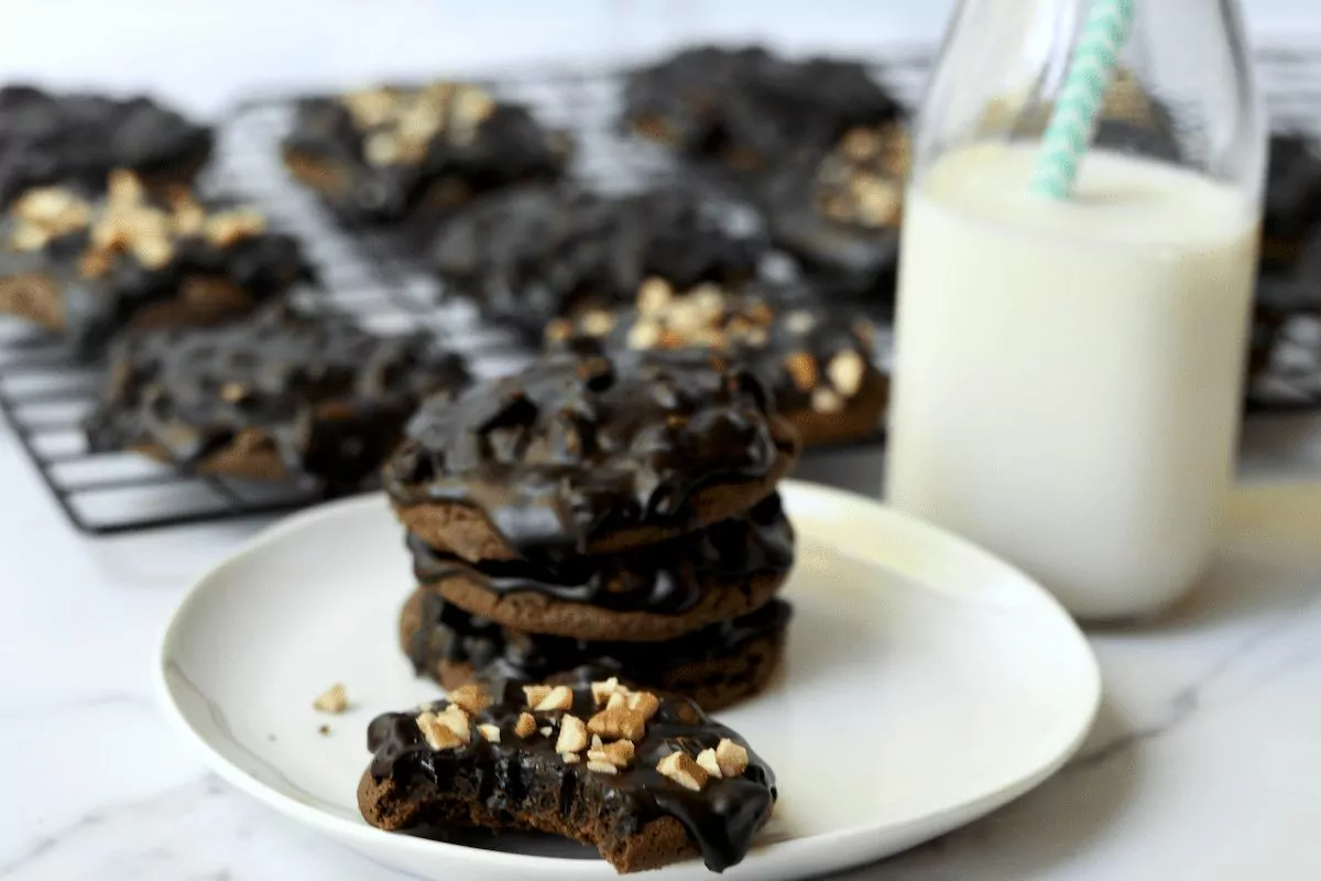 A plate of chocolate cookies with chocolate frosting and pecans over the top.