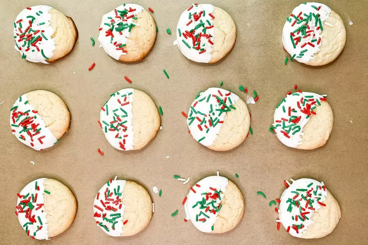 white cake mix cookies with frosting and sprinkles on parchment paper.