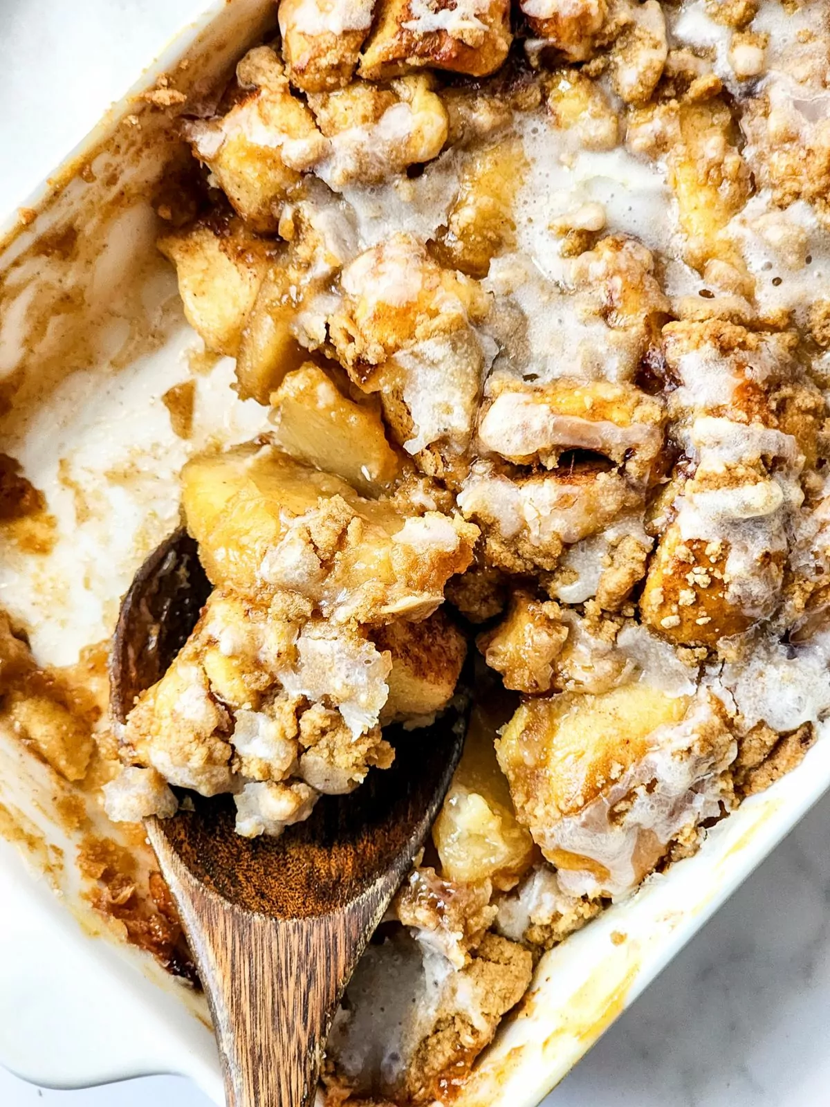 wooden spoon scooping up the apple cinnamon roll casserole