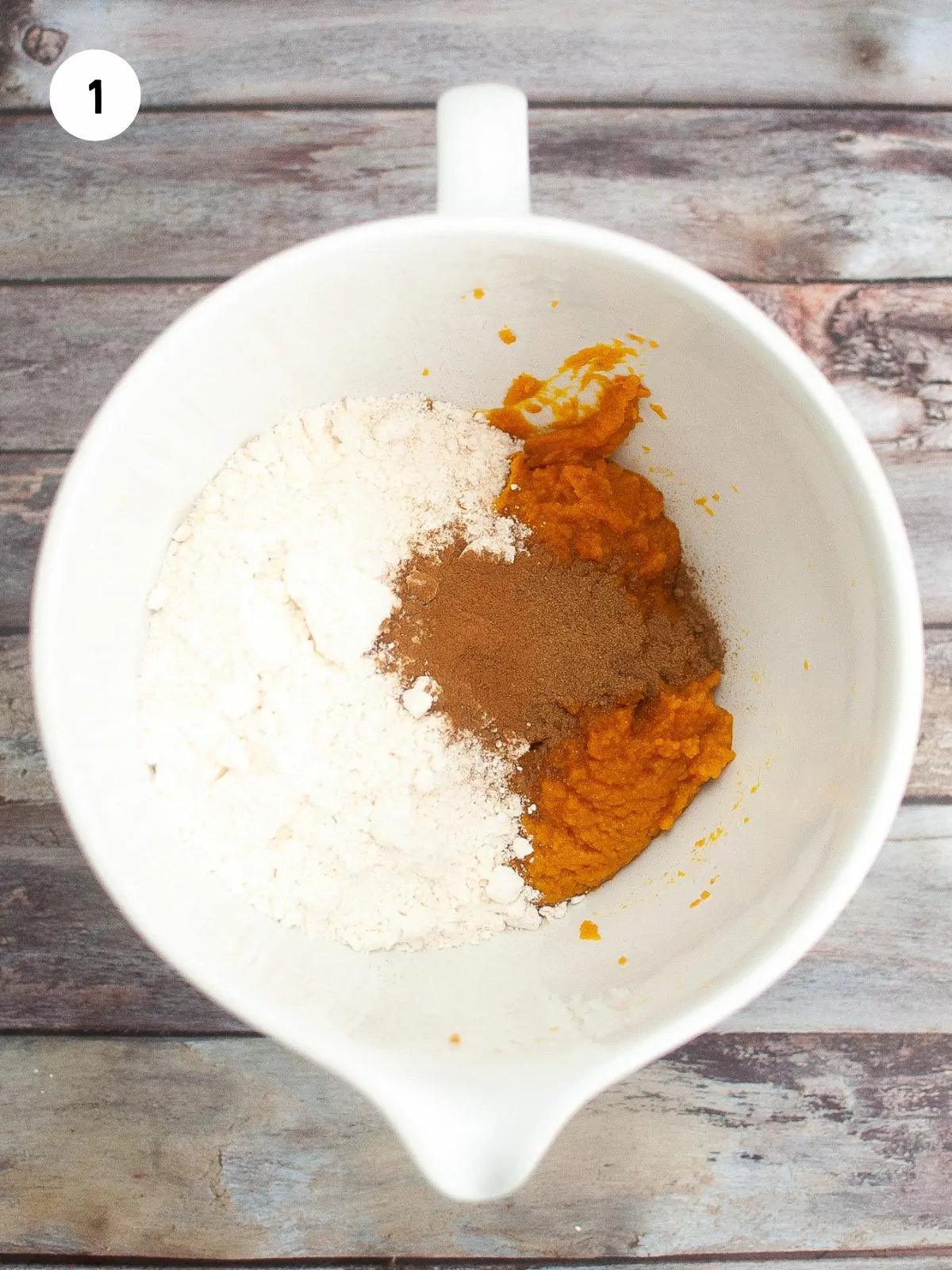 Cake mix, pumpkin puree, and spices in a white mixing bowl