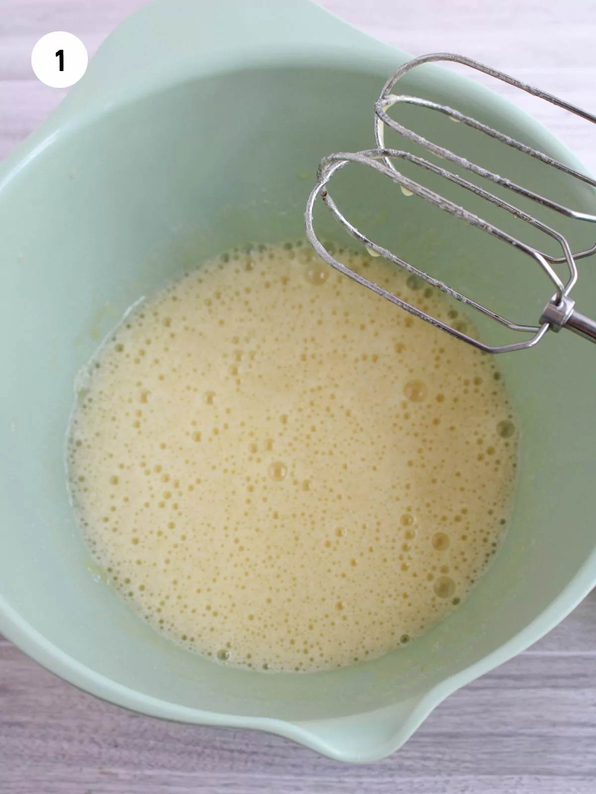 Sugar and eggs in mixing bowl beaten with hand mixer