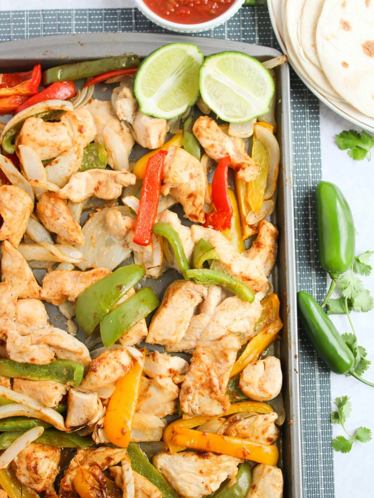 Sheet Pan Chicken Fajitas. Fresh, whole jalapenos, tortilla, and salsa next to the pan