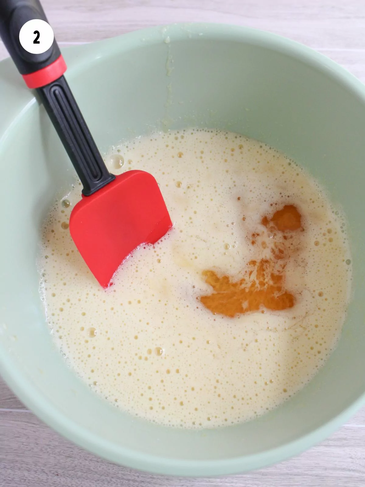 Vanilla and Karo syrup added to the egg mixture with a rubber spatula in the mixing bowl