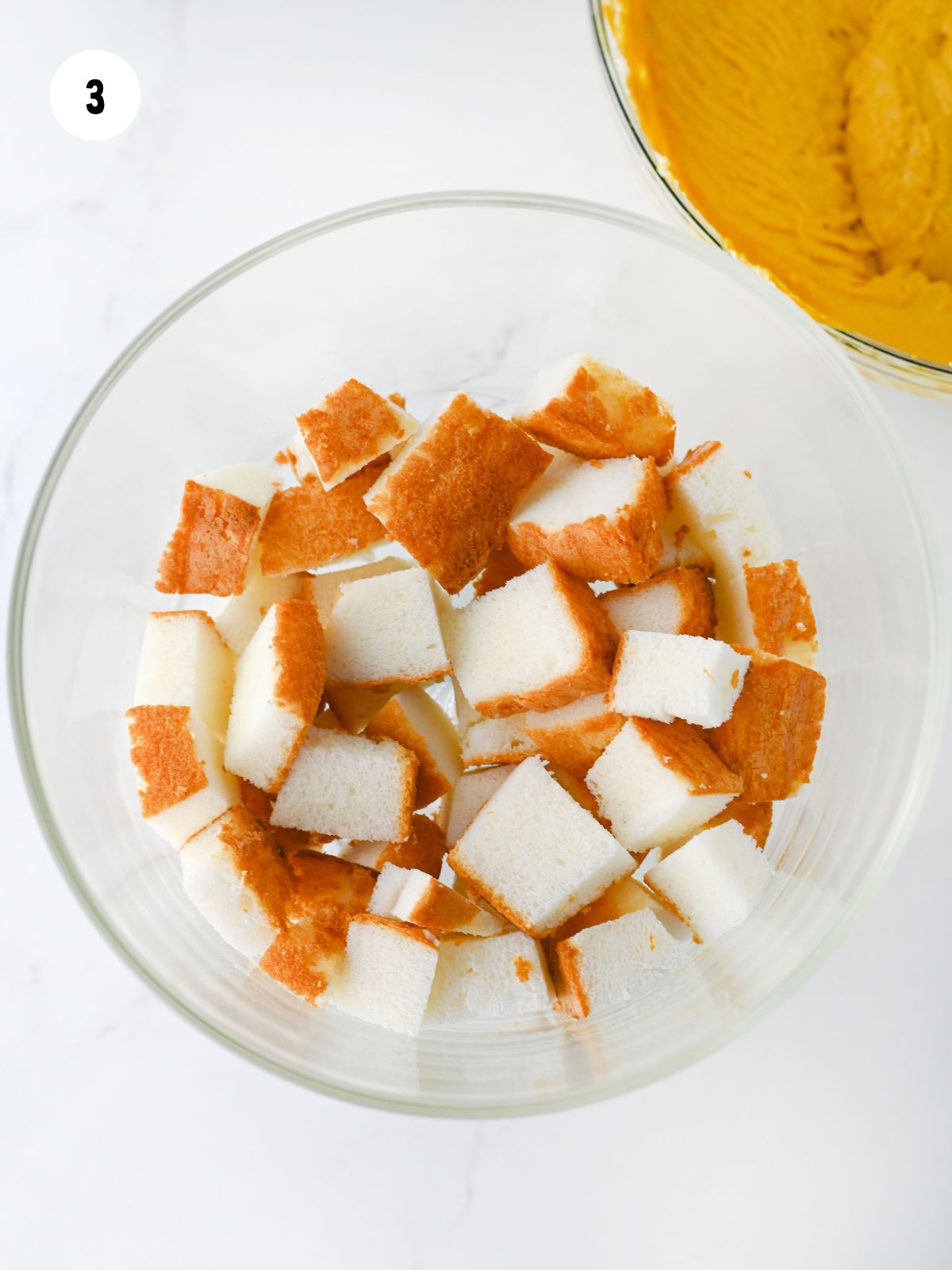 cubed angel food cake in the bottom of a trifle dish