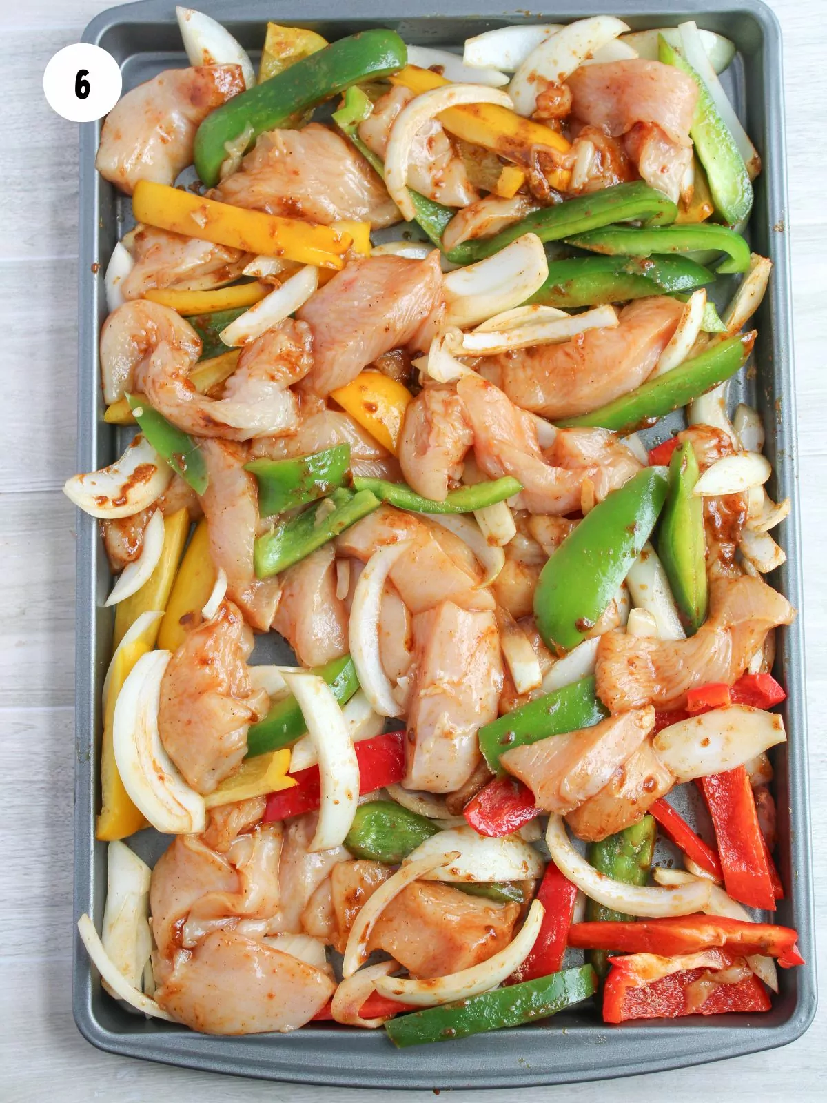 chicken and veggies coated in oil evenly spread out on the sheet pan