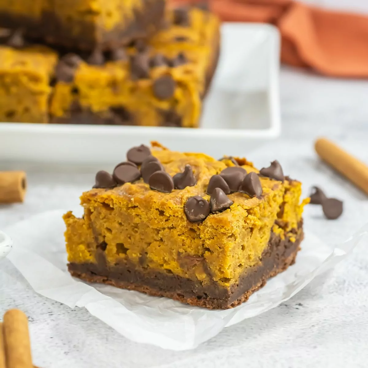 Pumpkin Brownie on a square of parchment with a platter in the background