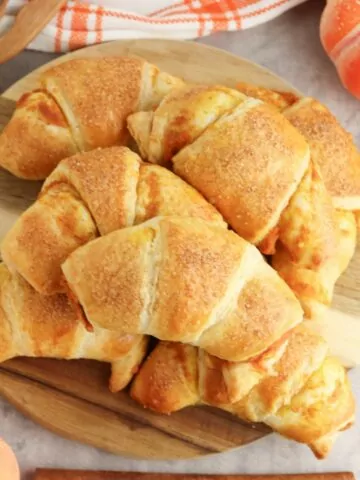 Pumpkin Cream Cheese Crescents piled onto a round wooden board