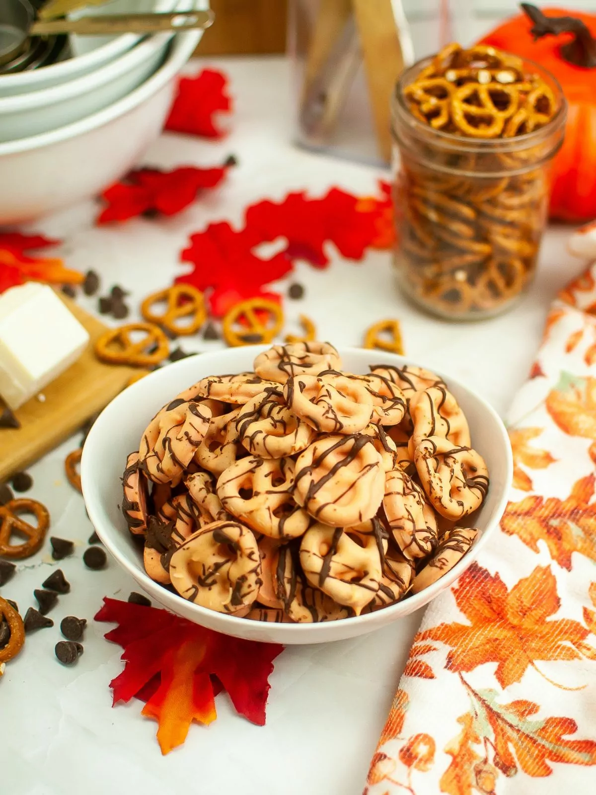 orange dipped pretzels for Halloween in white bowl.