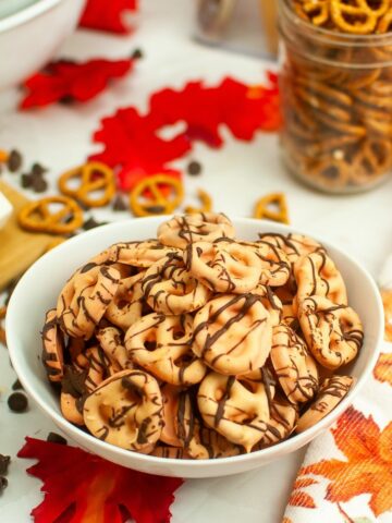 Bowl of orange pretzels with chocolate drizzle.