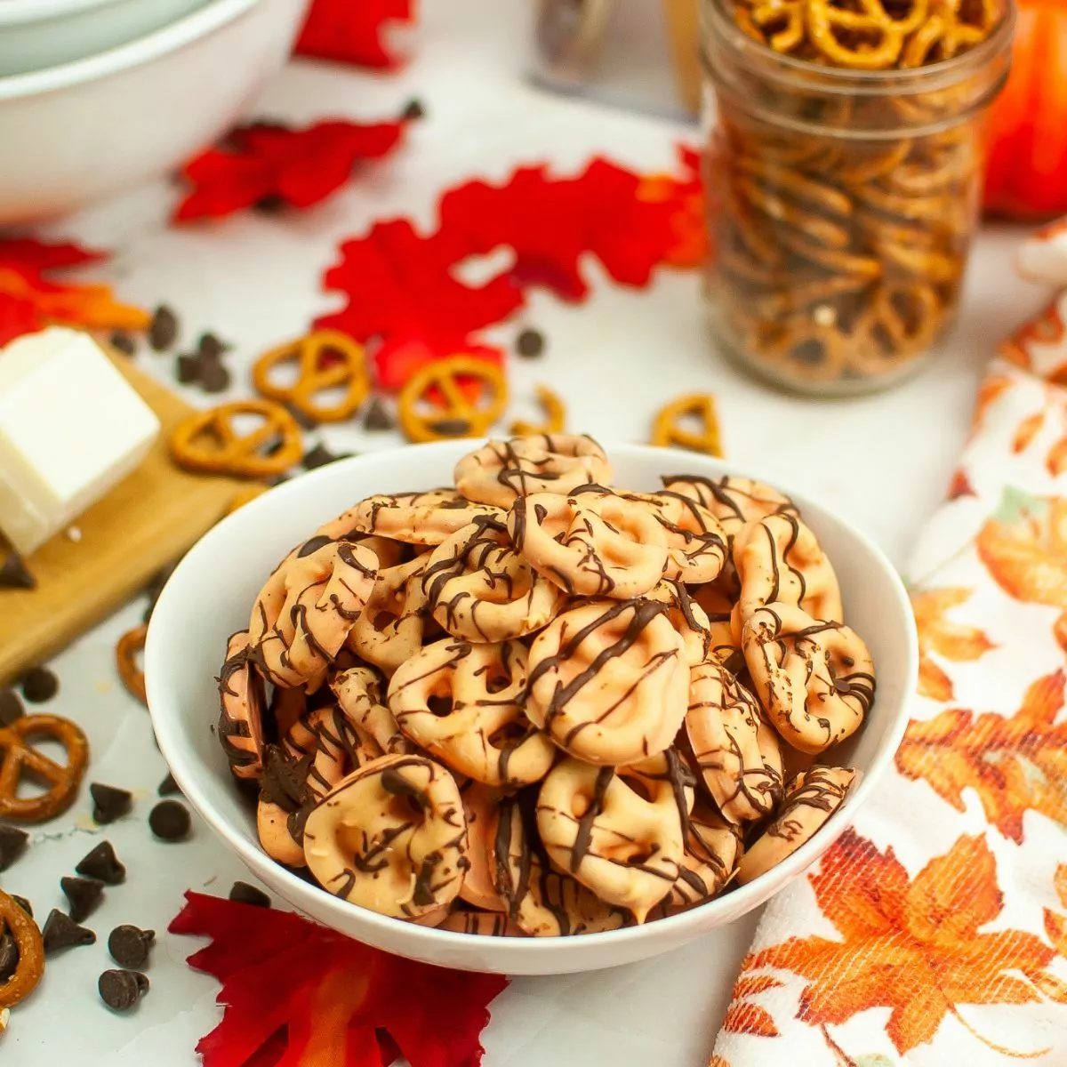 Bowl of orange pretzels with chocolate drizzle.