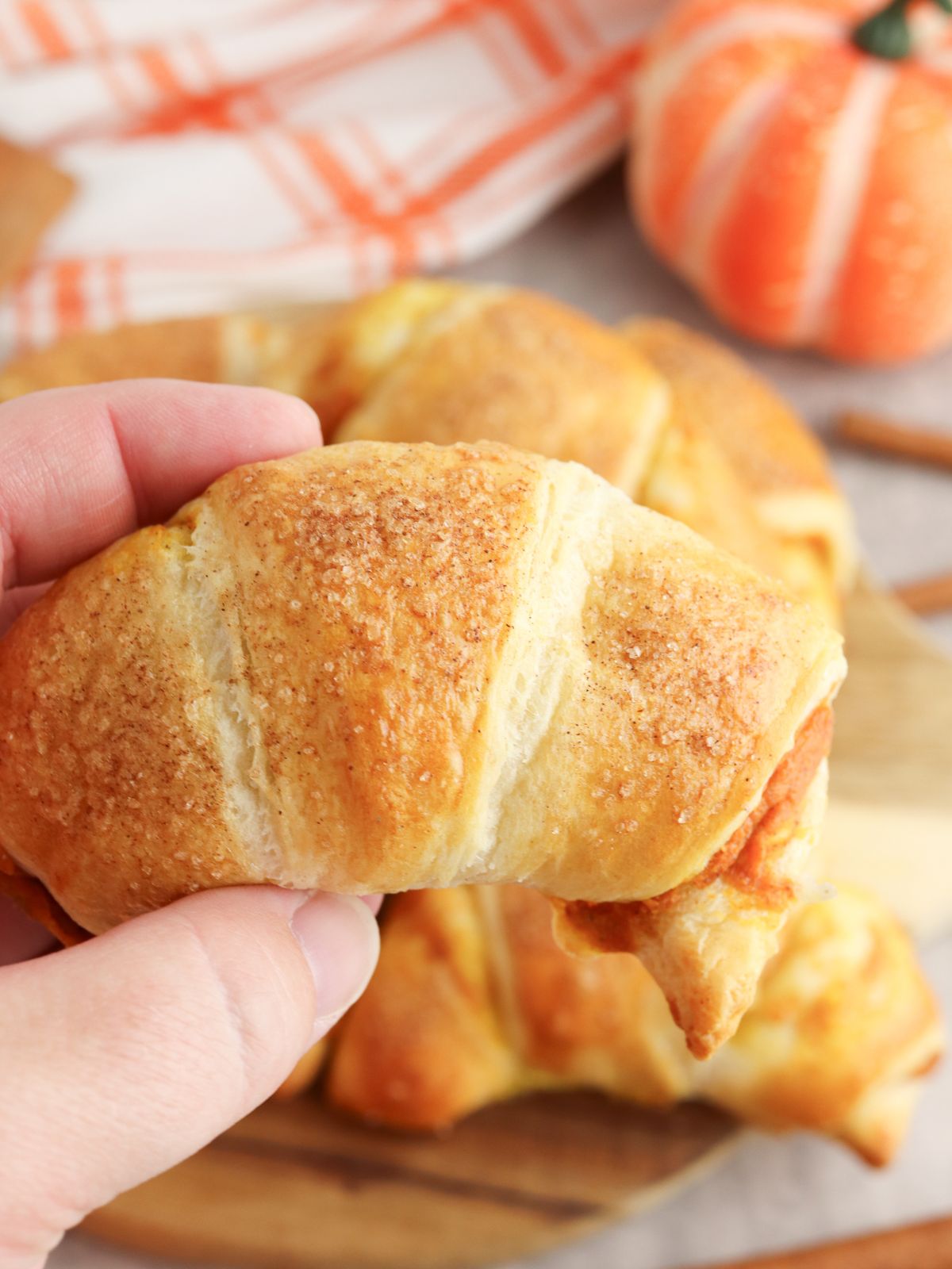 hand holding a baked crescent roll filled with pumpkin cream cheese