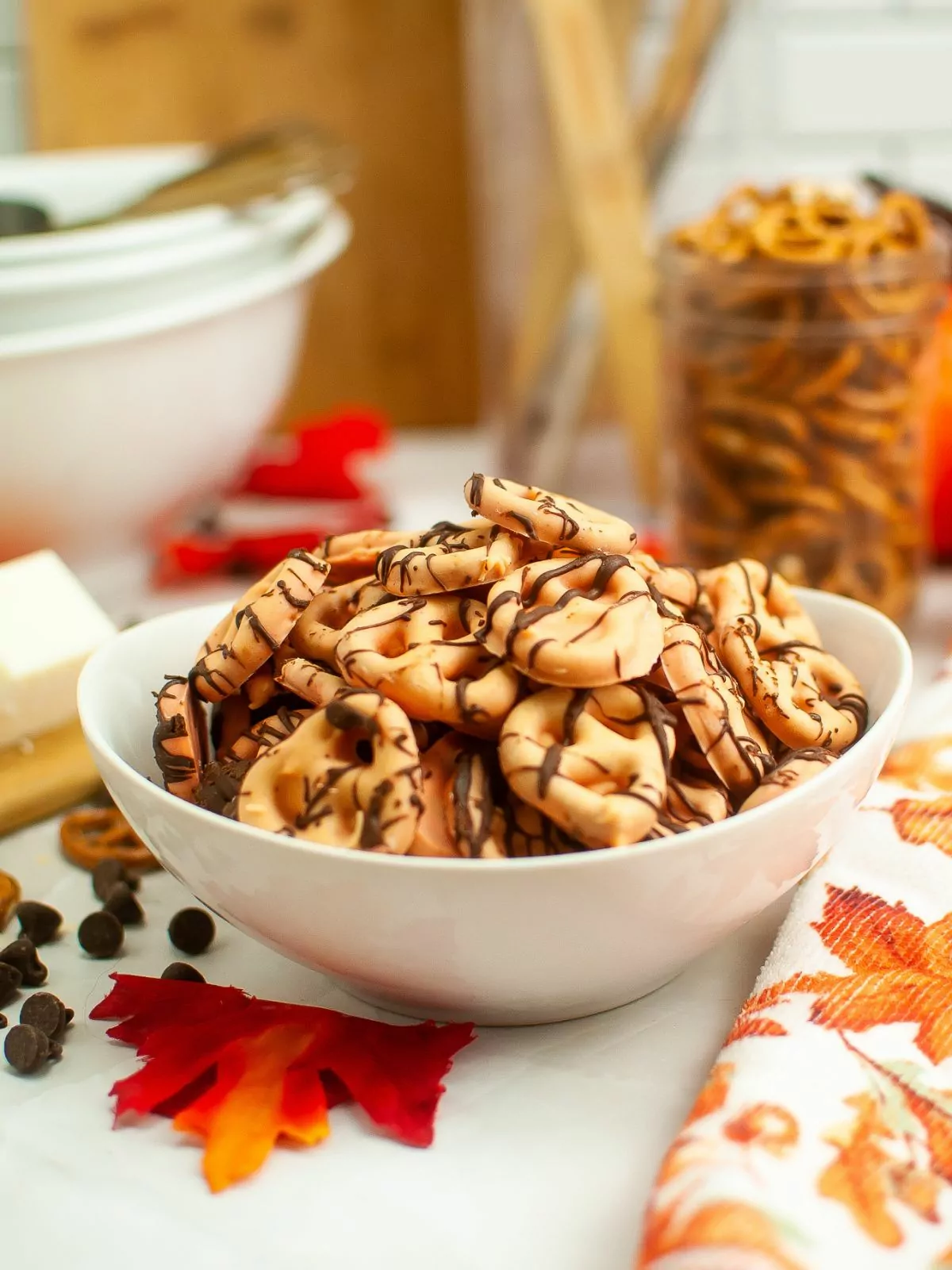 a bowl of chocolate covered pretzel twists drizzled with melted chocolate.