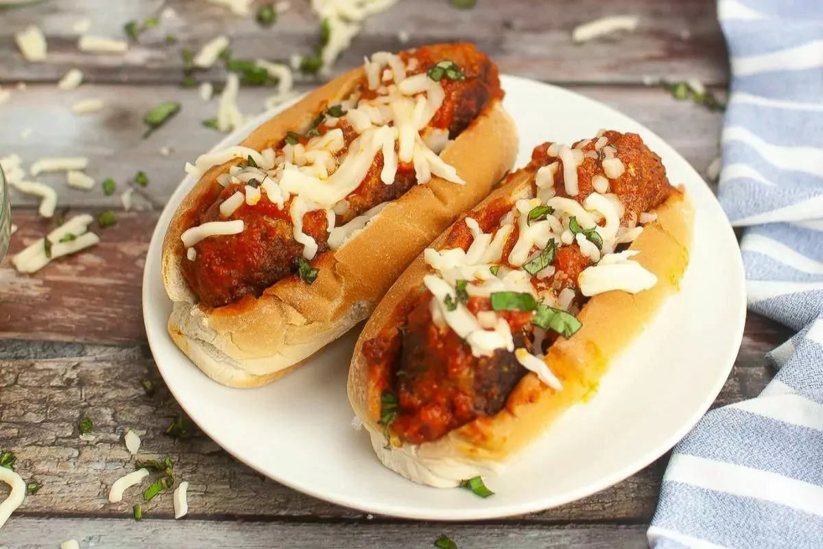 a plate of buns with meatballs and sauce and top with cheese