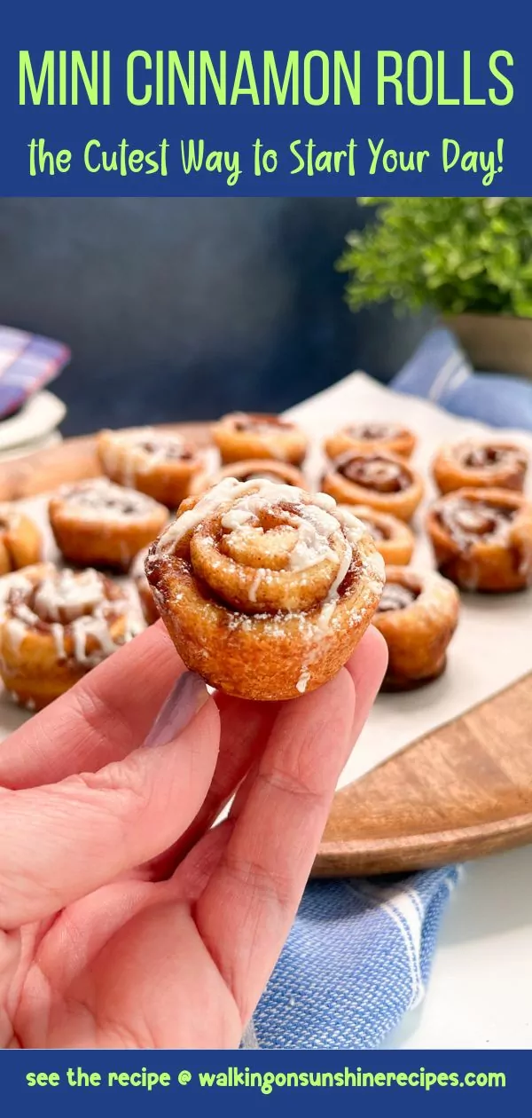 hand holding a mini cinnamon roll over a tray of more.