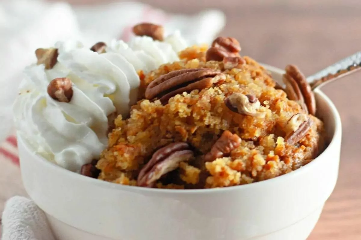 bowl of cobbler with whip cream and pecan nuts toppings