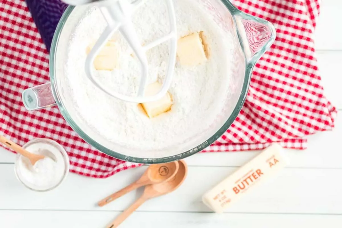 butter and flour in mixing bowl on top of red checked dish towel.