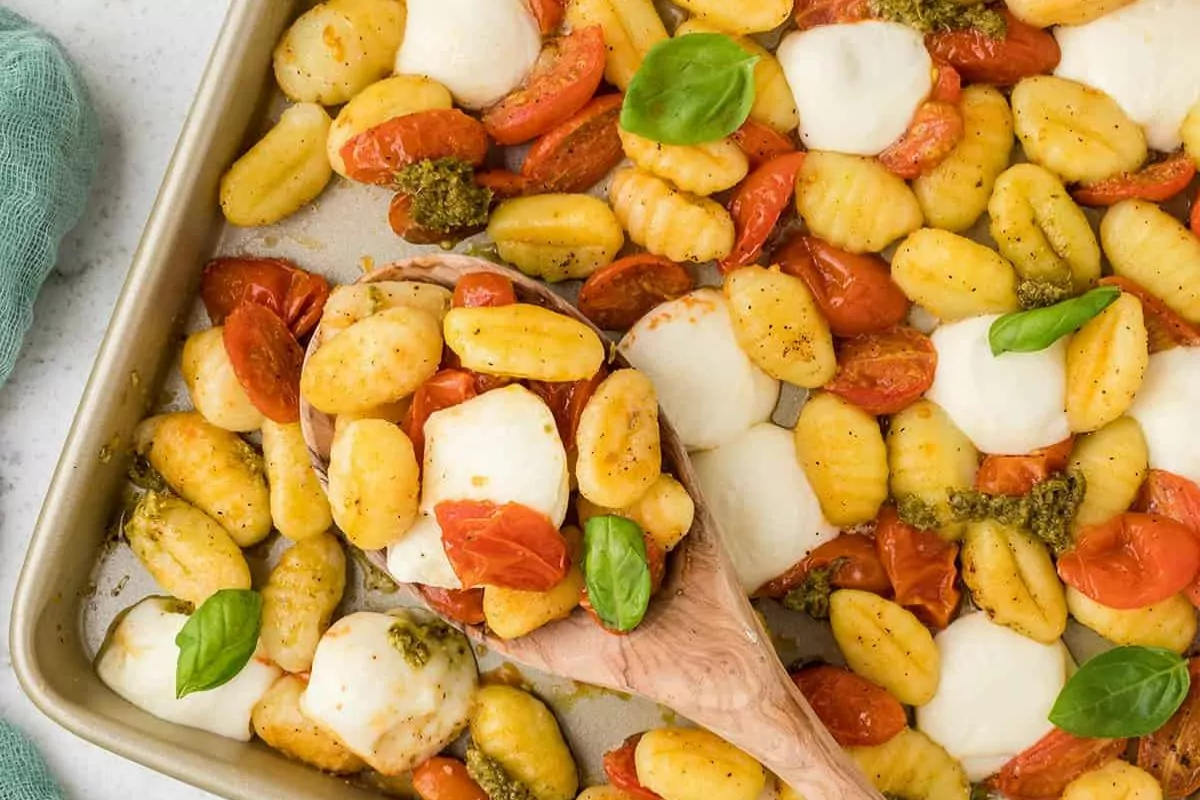 a sheet pan of baked gnocchi, tomato halves and chunks of cheese